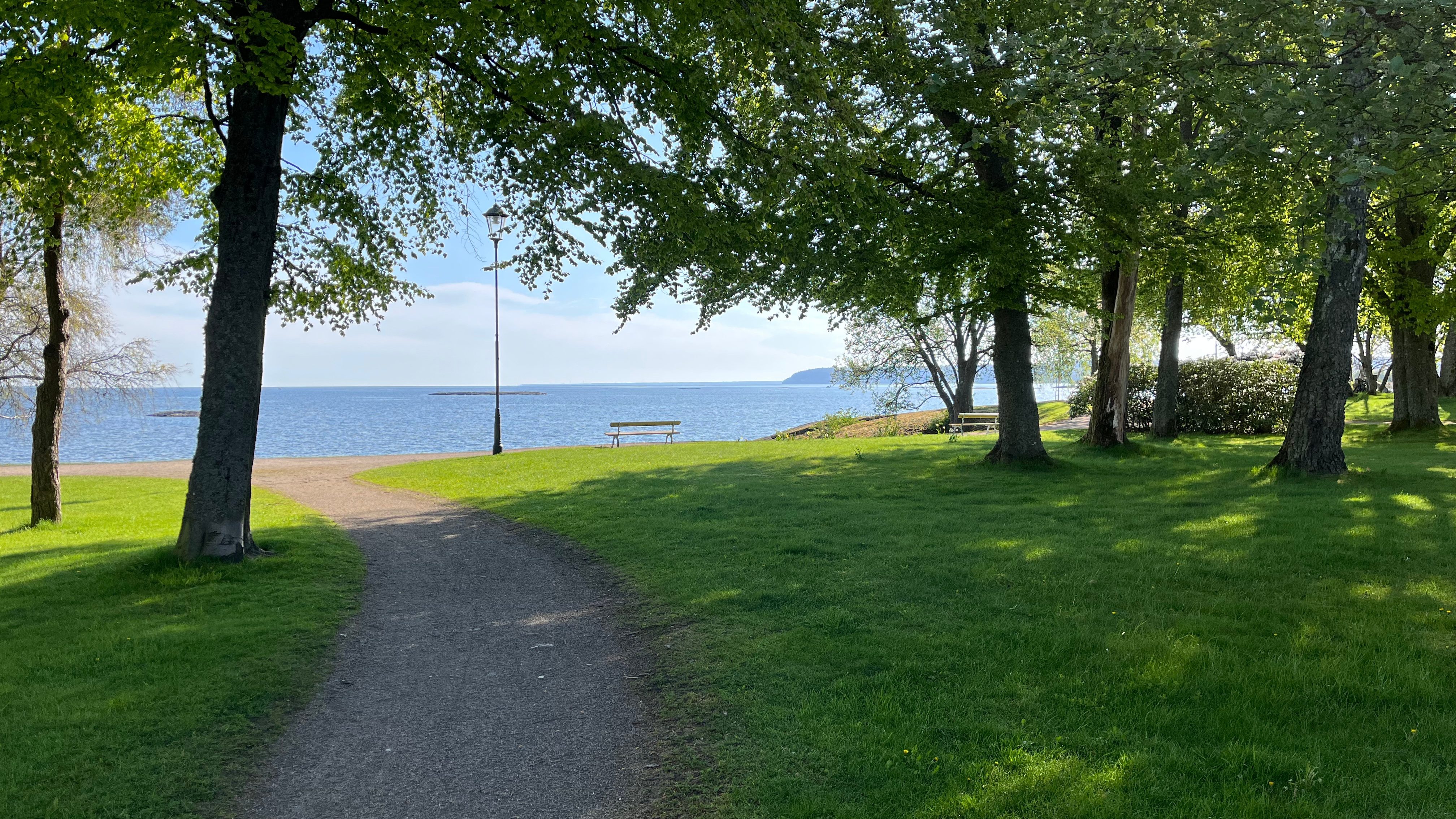 Bild av park med Vänern i bakgrunden